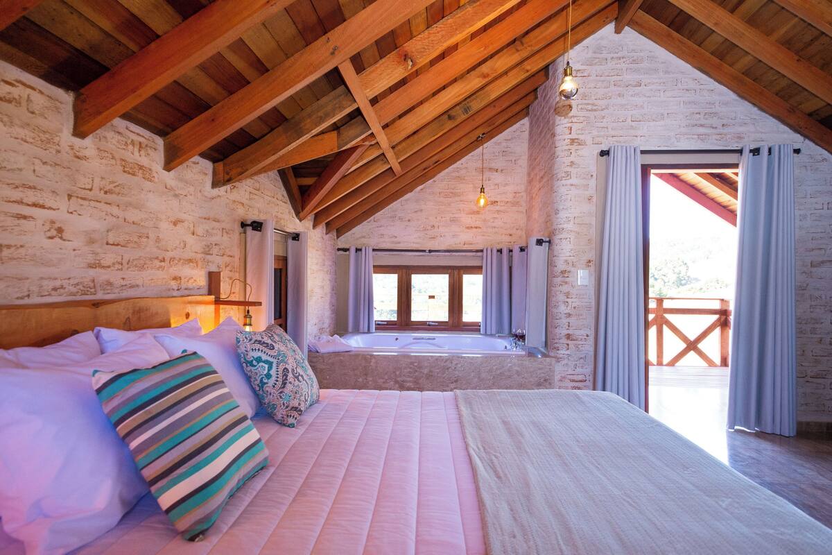 Une chambre avec un grand lit, un plafond en bois et une vue sur un balcon.