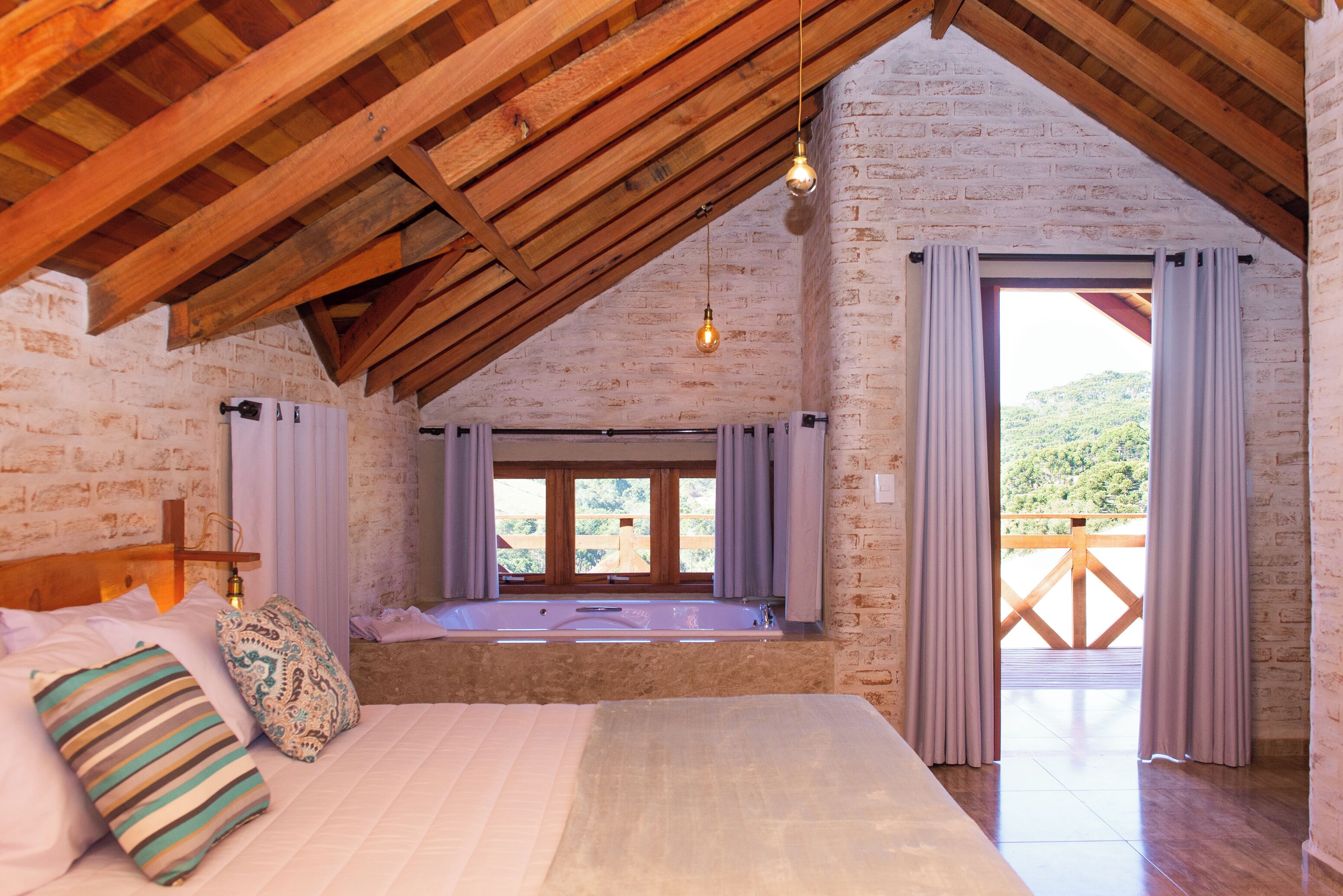 Une chambre avec un grand lit, un plafond en bois, une vue sur l’extérieur et une fenêtre avec des rideaux.