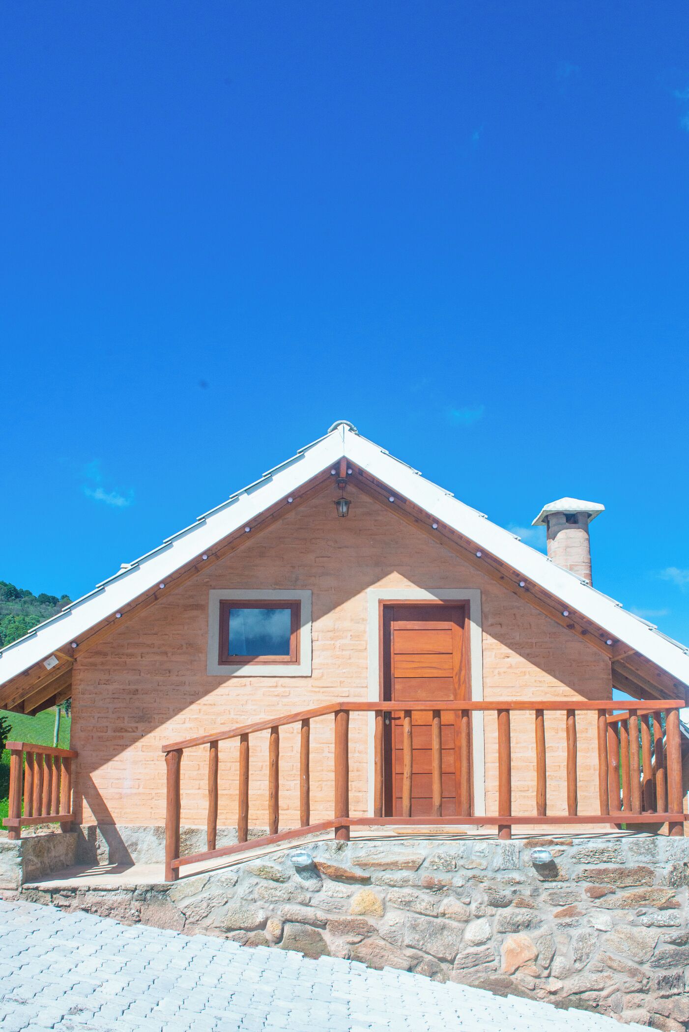 Un bâtiment en pierre avec une porte en bois et une petite fenêtre, un mur en pierre et une balustrade en bois.