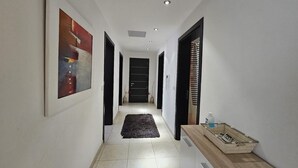 A hallway with a black rug, a wooden bench with a basket, and a door at the end.