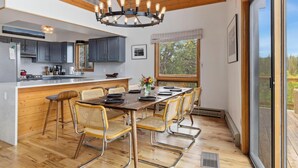 Een moderne keuken met een centraal eiland, houten vloeren en een eethoek met een grote tafel en stoelen.