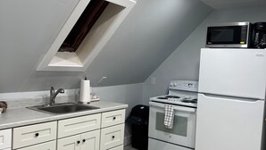 Una cocina moderna con armarios blancos, horno empotrado, microondas y refrigerador.