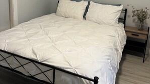 Un dormitorio con una cama, una mesita de noche y una pequeña mesa con un florero.