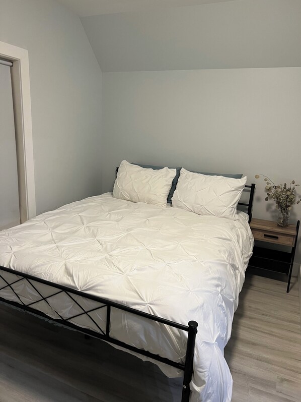 A bedroom with a bed, a nightstand, and a small table with a vase of flowers.