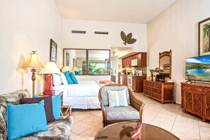 A hotel room with a bed, a sofa, a chair, a dining area, and a kitchen. - Maui Kaanapali Villas MKV-C255 by KBM (Kaanapali)
