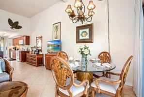 Zona pranzo con tavolo in vetro, sedie in vimini e lampadario.