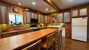 A kitchen with wooden cabinets, a stove, a refrigerator, and a large island with chairs. - Charming 1-bedroom apartment in Oxford (Oxford)