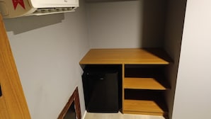 A compact room with a wooden desk, a black refrigerator, and a small shelf unit. - Casa Pé na Areia (Fernando de Noronha)