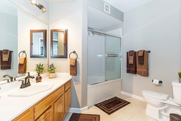 Une salle de bain moderne avec une douche en verre, des toilettes blanches et un meuble-lavabo en bois.