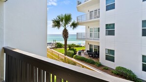 A balcony with a view of a white building, a palm tree, and the ocean. - 60 Secs to [Private] Beach Seagrove - Gulf views! (Seagrove)