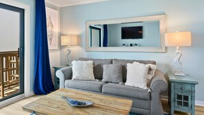 A living room with a grey sofa, a wooden coffee table, and a TV mounted above a mirror. - 60 Secs to [Private] Beach Seagrove - Gulf views! (Seagrove)