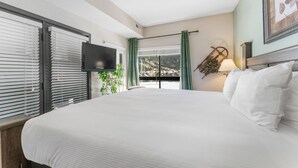 A hotel room with a large bed, a flat-screen TV mounted on the wall, and a view of a mountainous landscape through the window. - Gac314c2 (Copper Mountain)