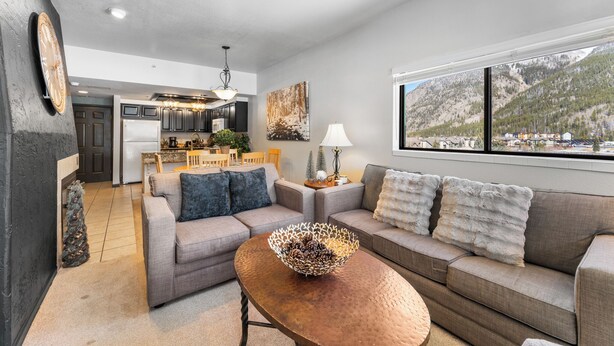 A modern living room with a sofa, coffee table, and a view of mountains through large windows. - Gac314c2 (Copper Mountain)