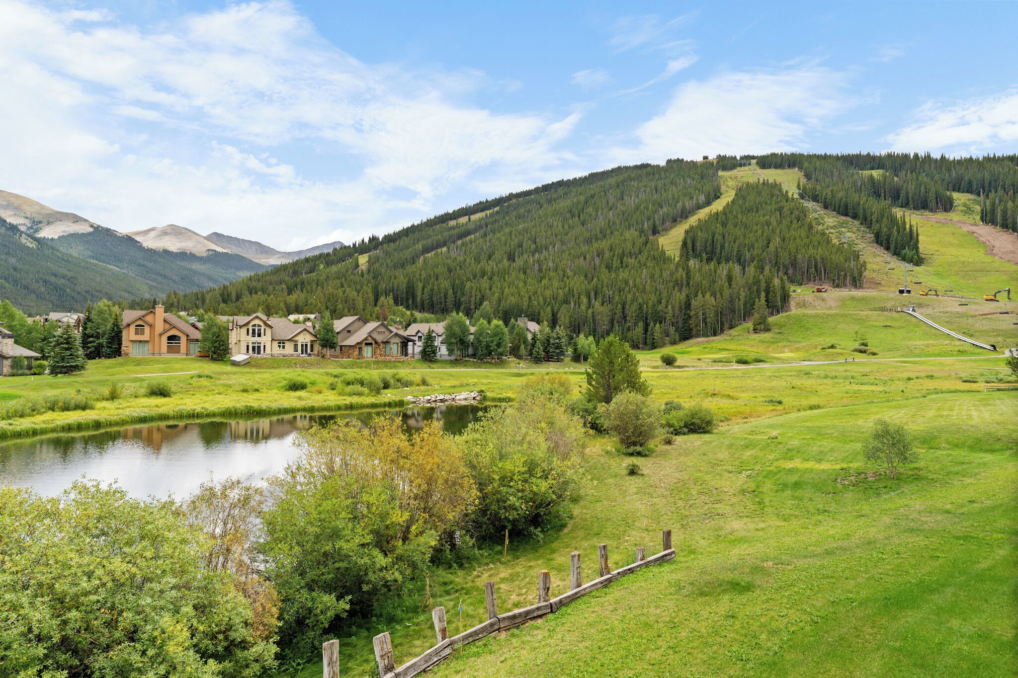 Zona residencial amb cases, un estany i un turó forestat.