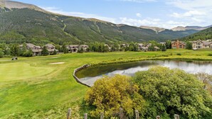 A golf course with a pond, houses, and mountains in the background. - Gac214c1 (Copper Mountain)
