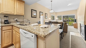 A kitchen with granite countertops, wooden cabinets, a dishwasher, and a dining area with a table and chairs. - Gac214c1 (Copper Mountain)