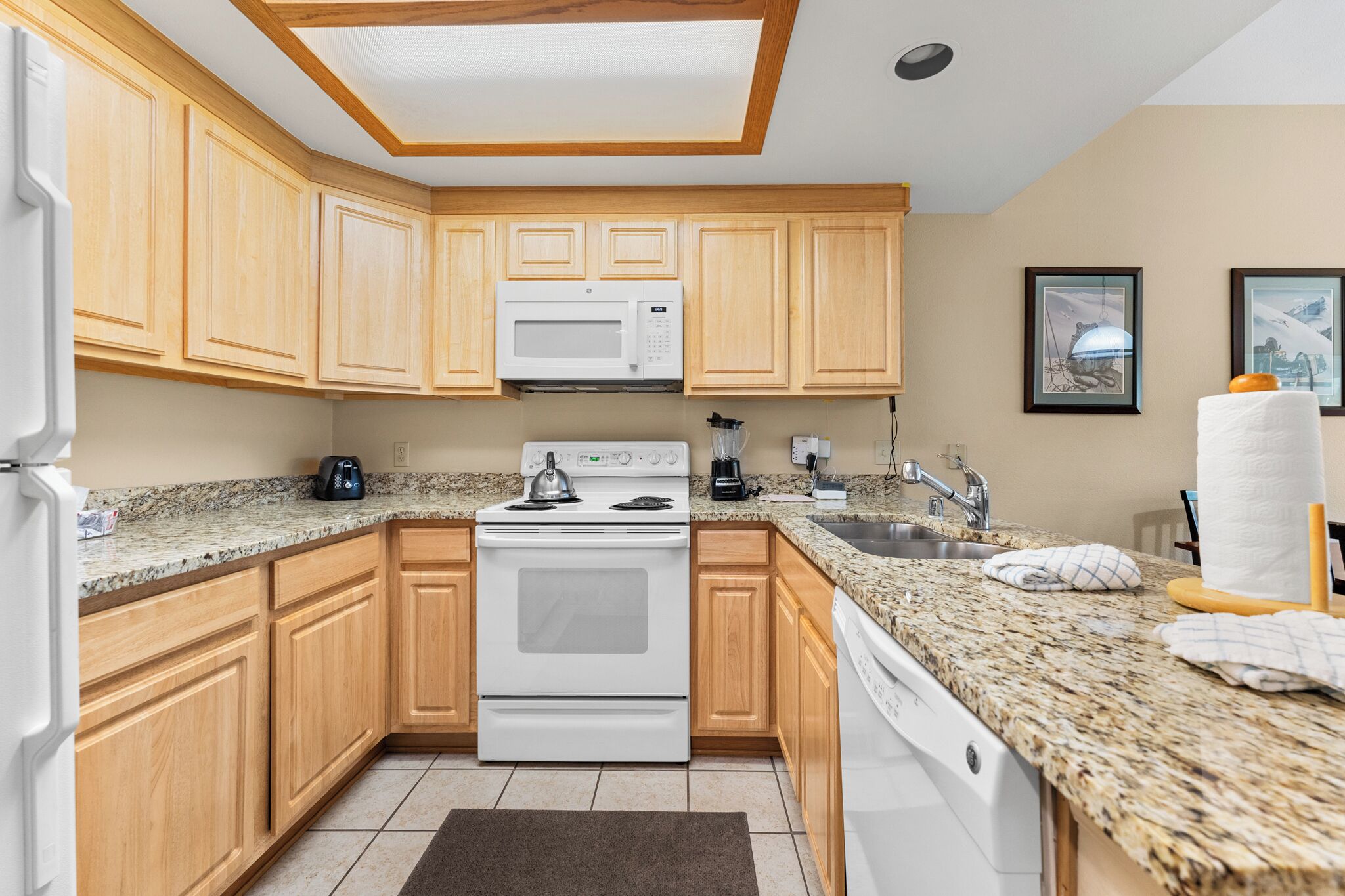 A kitchen with wooden cabinets, a white stove, a microwave, and granite countertops.