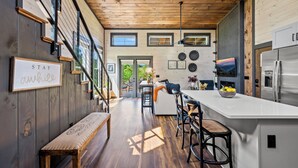 Une cuisine moderne dotée d’un grand îlot central, de planchers en bois et offrant une vue sur l’extérieur.
