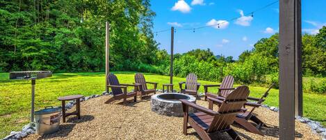 An outdoor seating area with Adirondack chairs, a fire pit, and a gravel ground.