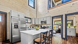 Une cuisine moderne dotée d’un îlot central, d’appareils électroménagers en acier inoxydable et d’un revêtement de sol en bois.