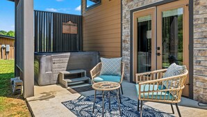 Un espace extérieur aménagé en terrasse, avec des fauteuils en osier, un jacuzzi et un mur en pierre.