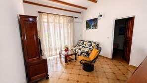 A room with a wooden cabinet, a glass coffee table, a patterned sofa, and a tiled floor. - La Casa Créole, spa, 3 BR, 2 baths, center of Guadeloupe (Les Abymes)