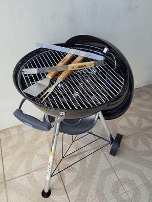 Ein tragbarer Grill mit Tragegriff, Deckel und zwei Pfannenwendern.