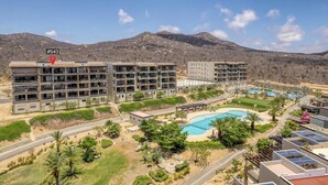 Un hotel con diversi piani, una piscina e montagne sullo sfondo.