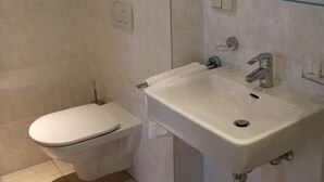 Ein modernes Badezimmer mit Toilette, Waschbecken und Duschkabine aus Glas.