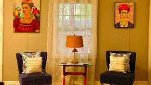 A living room with two armchairs, a glass coffee table, a lamp, and two paintings on the wall.