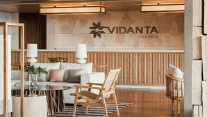 Um lobby moderno com uma mesa de recepção de madeira, um sofá e uma poltrona.