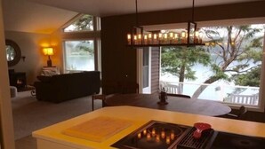 Una cocina moderna con estufa integrada, encimera amarilla y vistas al exterior a través de amplios ventanales.