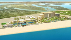 A coastal resort with multiple buildings, a swimming pool, and a beach area.