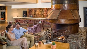 A lobby with a large stone fireplace, comfortable seating, and a reception desk.