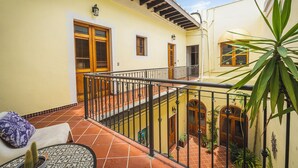 A courtyard with a tiled floor, a wooden bench, a cactus plant, and a railing. - Quiet Romantic Retreat: Walk Everywhere • King Bed • Historic Charm (San Juan)
