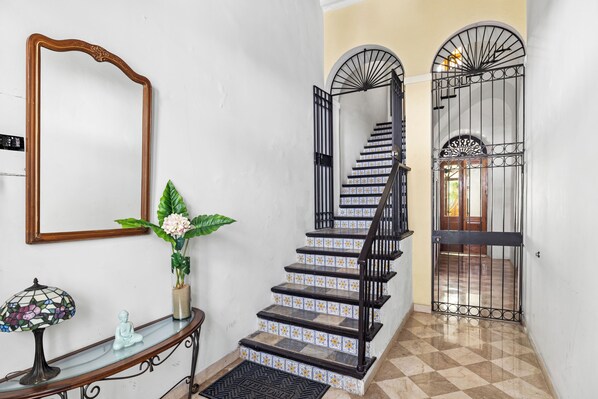 A staircase with black railings, a mirror, a vase with a plant, and a small Buddha statue.