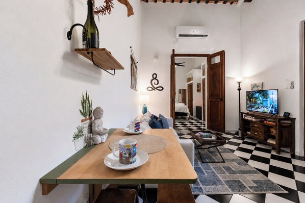 A dining area with a wooden table, a television, and a checkered floor.