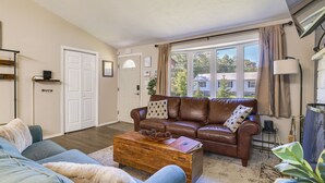 Un salon avec un canapé en cuir marron, un fauteuil bleu et une table basse en bois.