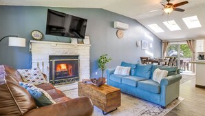 Un salon avec une cheminée, un téléviseur et un coin repas comprenant une table et des chaises.