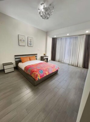 Relax in a spacious room with a large bed, two bedside tables, and a large window.