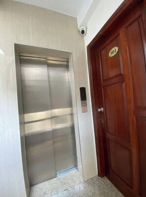 Access the upper floors via this elevator, featuring a control panel and traditional door with a brass handle.