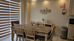A dining area with a table, chairs, a chandelier, a fire extinguisher, and a trash bin. - Beautiful Home backing on Welland Canals STR-289 (Welland)