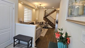 A home interior with a staircase, a sofa, a bench, and a welcome sign. - Beautiful Home backing on Welland Canals STR-289 (Welland)