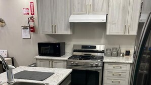 A modern kitchen with stainless steel appliances, white cabinetry, and a tiled floor. - Beautiful Home backing on Welland Canals STR-289 (Welland)