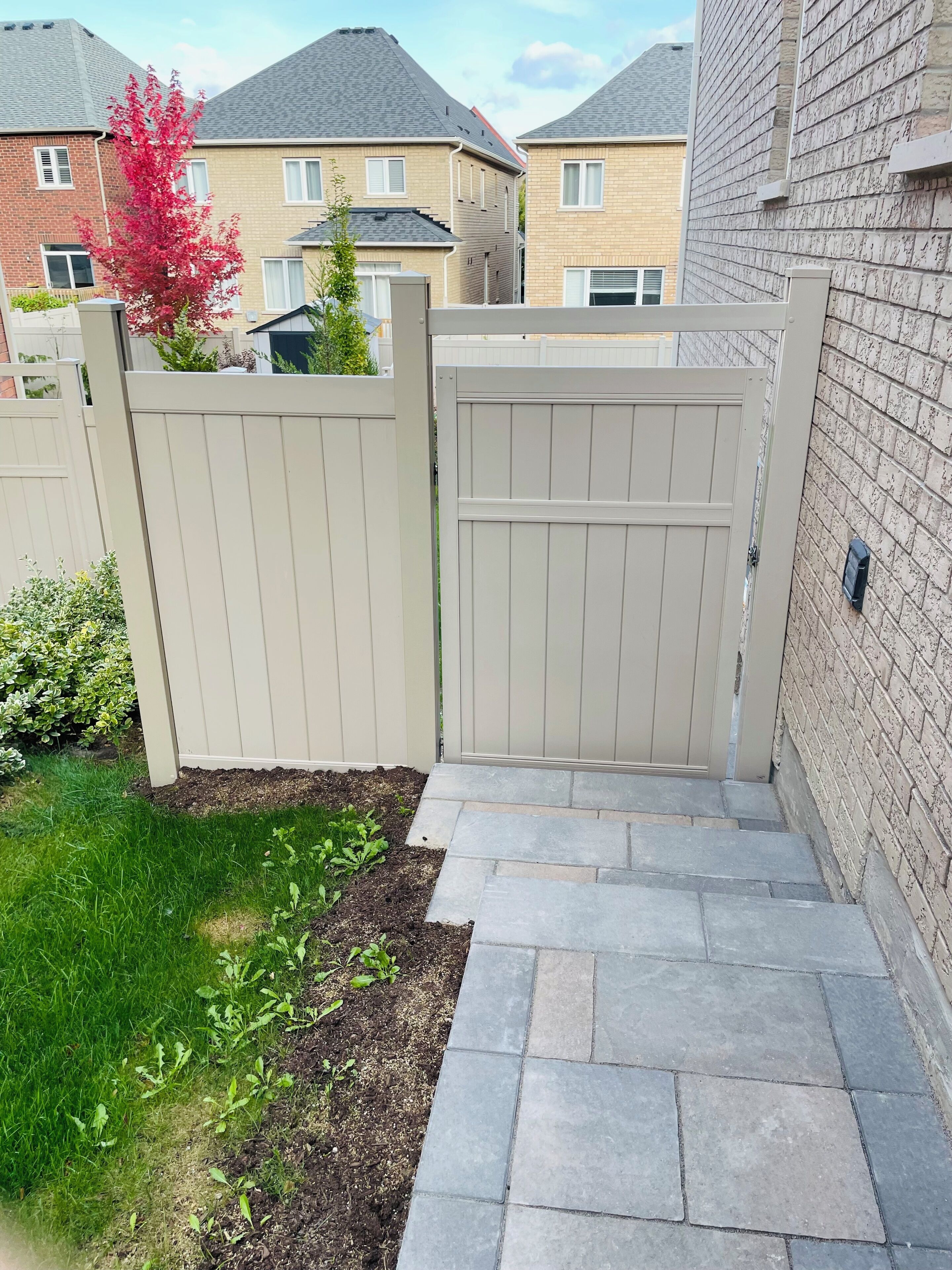 Ein durch eine Mauer abgegrenzter Garten mit einem steinbelagten Weg, der zu einem Haus führt.