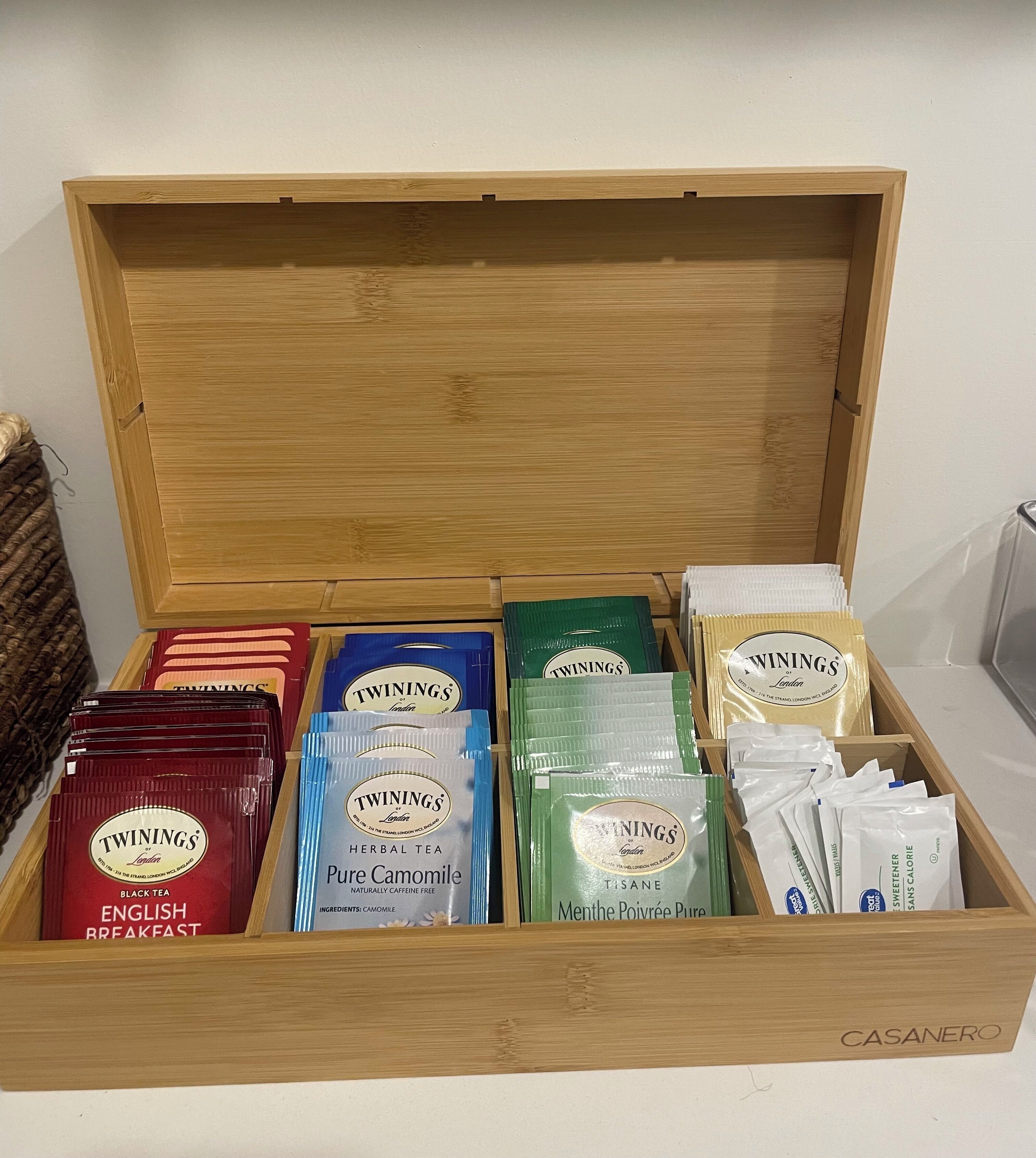 A wooden box containing various Twinings tea products.