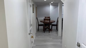 A hallway with a dining table and chairs, white walls, and a light wood floor. - New, Clean and Comfortable Apartment with Private Entrance.  (East Gwillimbury)