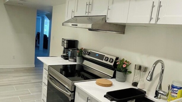 A modern kitchen with white cabinets, stainless steel appliances, and a black sink. - New, Clean and Comfortable Apartment with Private Entrance.  (East Gwillimbury)