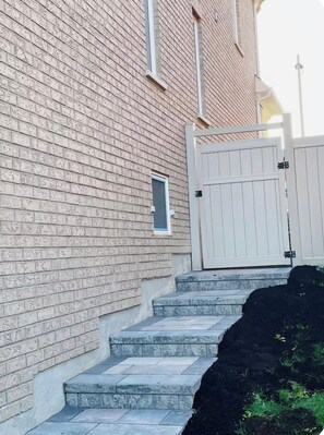 Un edificio de ladrillo con una reja blanca y escalones que conducen a una puerta.