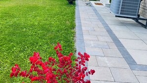 A residential area with a well-maintained lawn, a red flowering shrub, and a brick building with a balcony. - New, Clean and Comfortable Apartment with Private Entrance.  (East Gwillimbury)